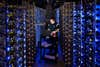 Google employee working in a circle of lit-up computer servers in a dark data center
