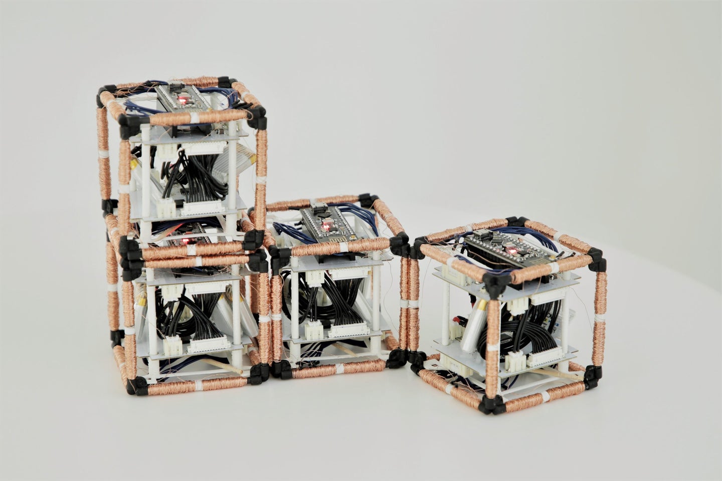 four cubes with copper wires wrapped around their edges that are connected electromagnetically