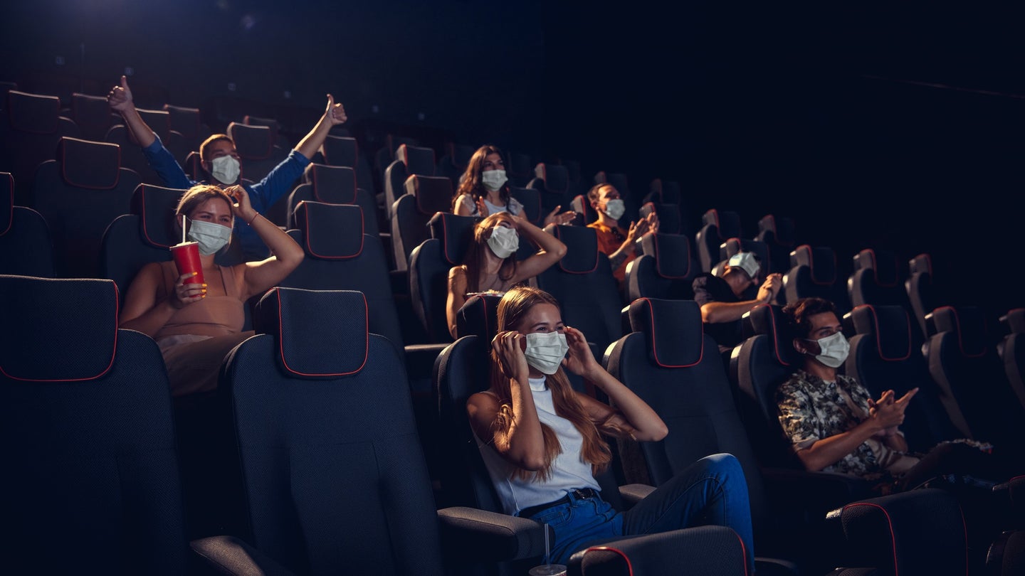 People wearing COVID surgical masks in a dark movie theater