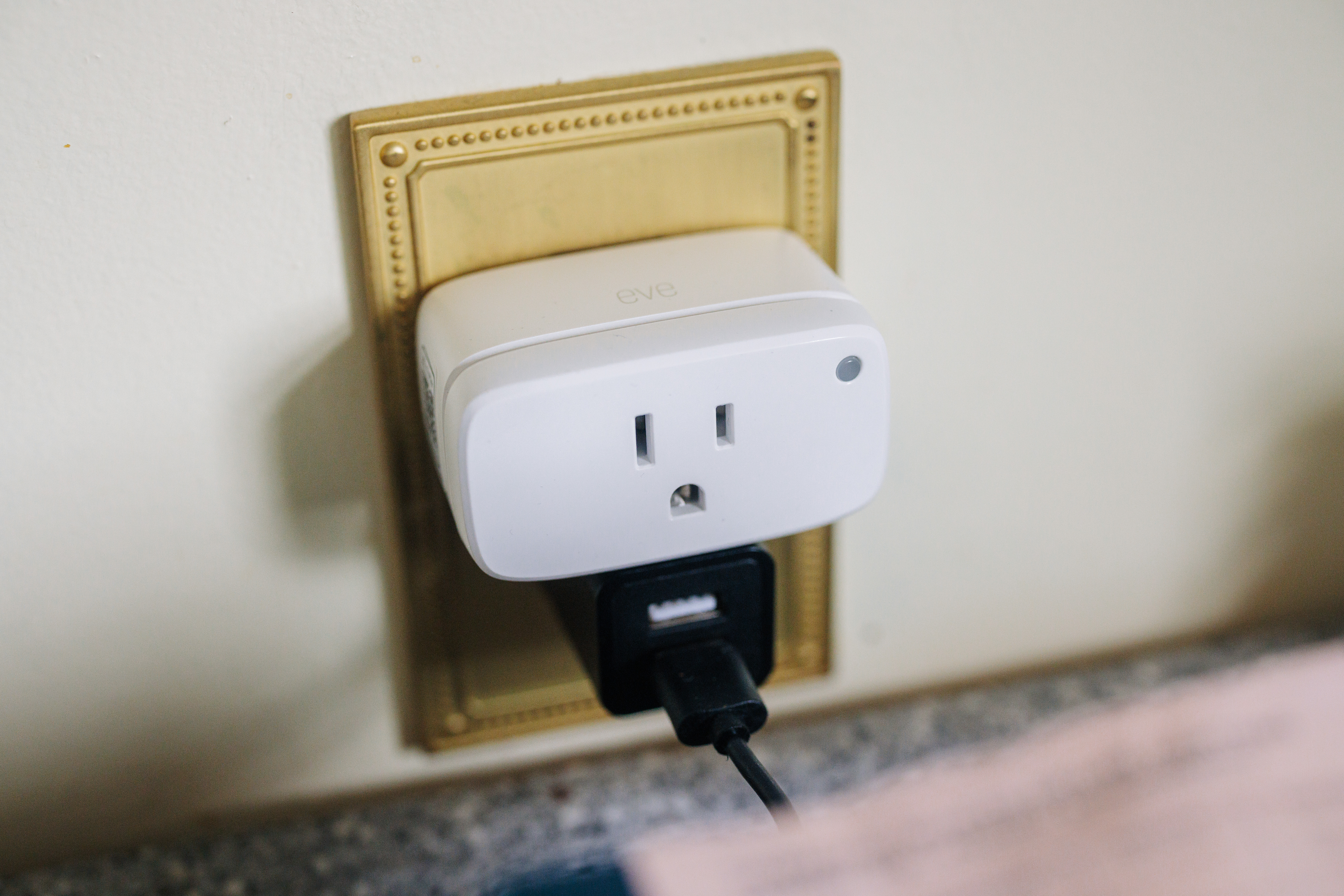 Eve Smart Plug and power meter plugged into an outlet with another power brick