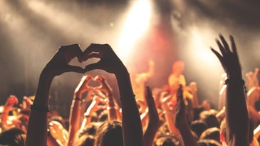 Person-doing-heart-hand-gesture-at-concert