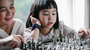 old woman and girl play chess inside the house
