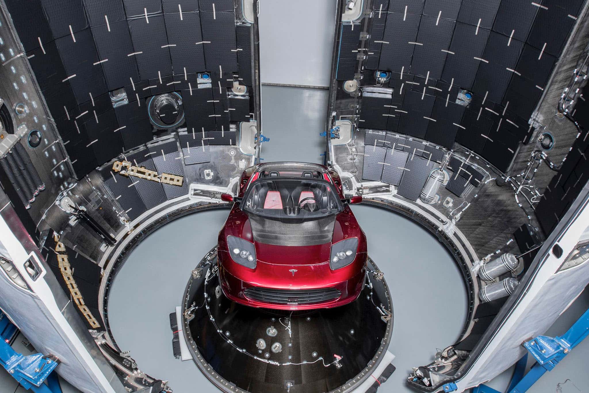 Red Tesla Roadster being loaded into a rocket capsule during Elon Musk's SpaceX launch in 2018