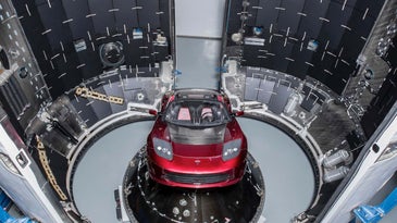 Red Tesla Roadster being loaded into a rocket capsule during Elon Musk's SpaceX launch in 2018