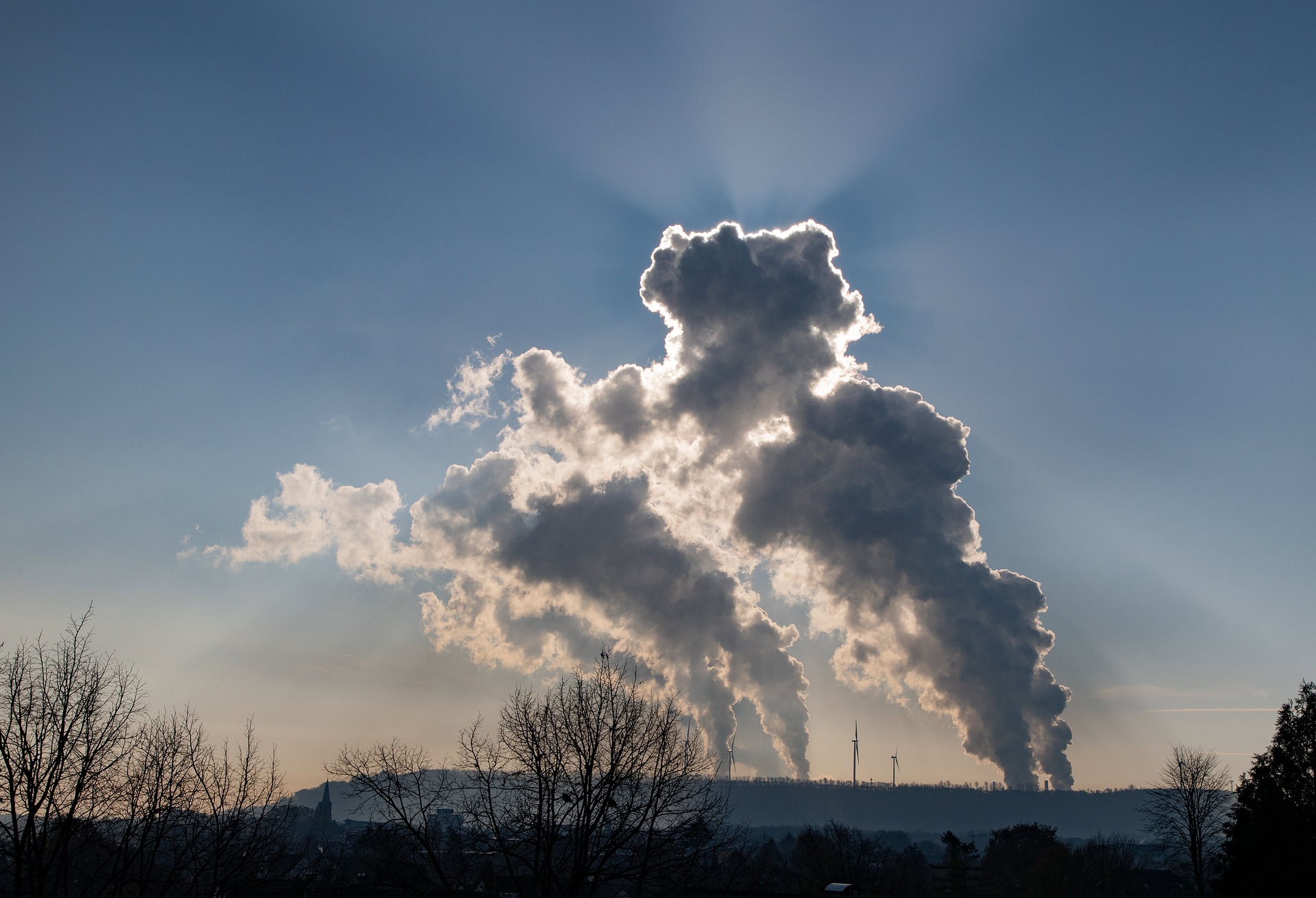 Smoke stack releasing carbon emissions on a sunny horizon