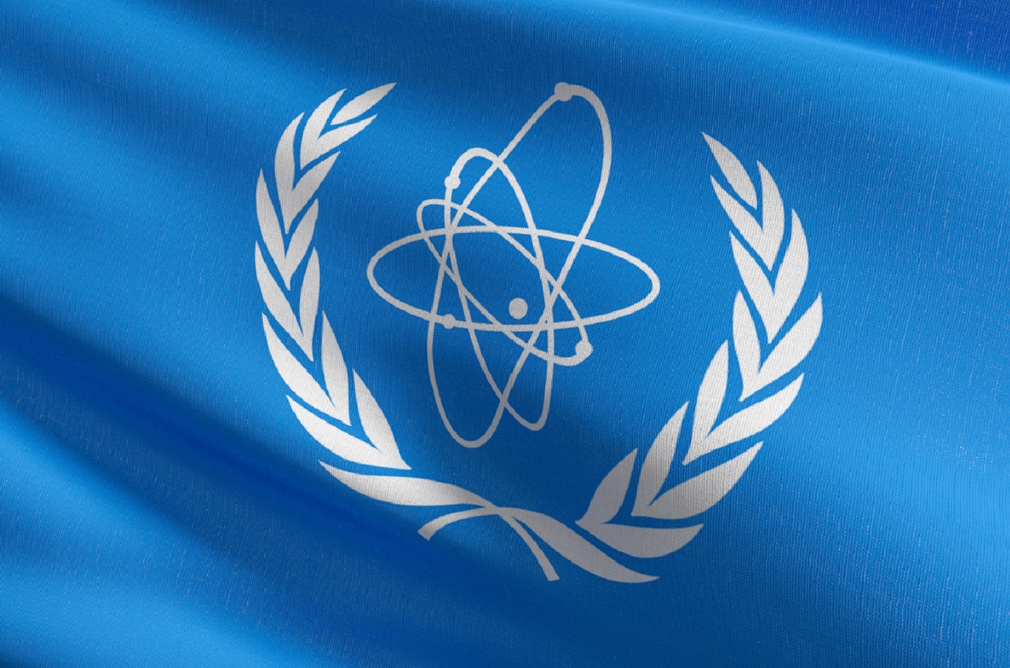 Light blue flag with IEAE nuclear energy logo in middle in white