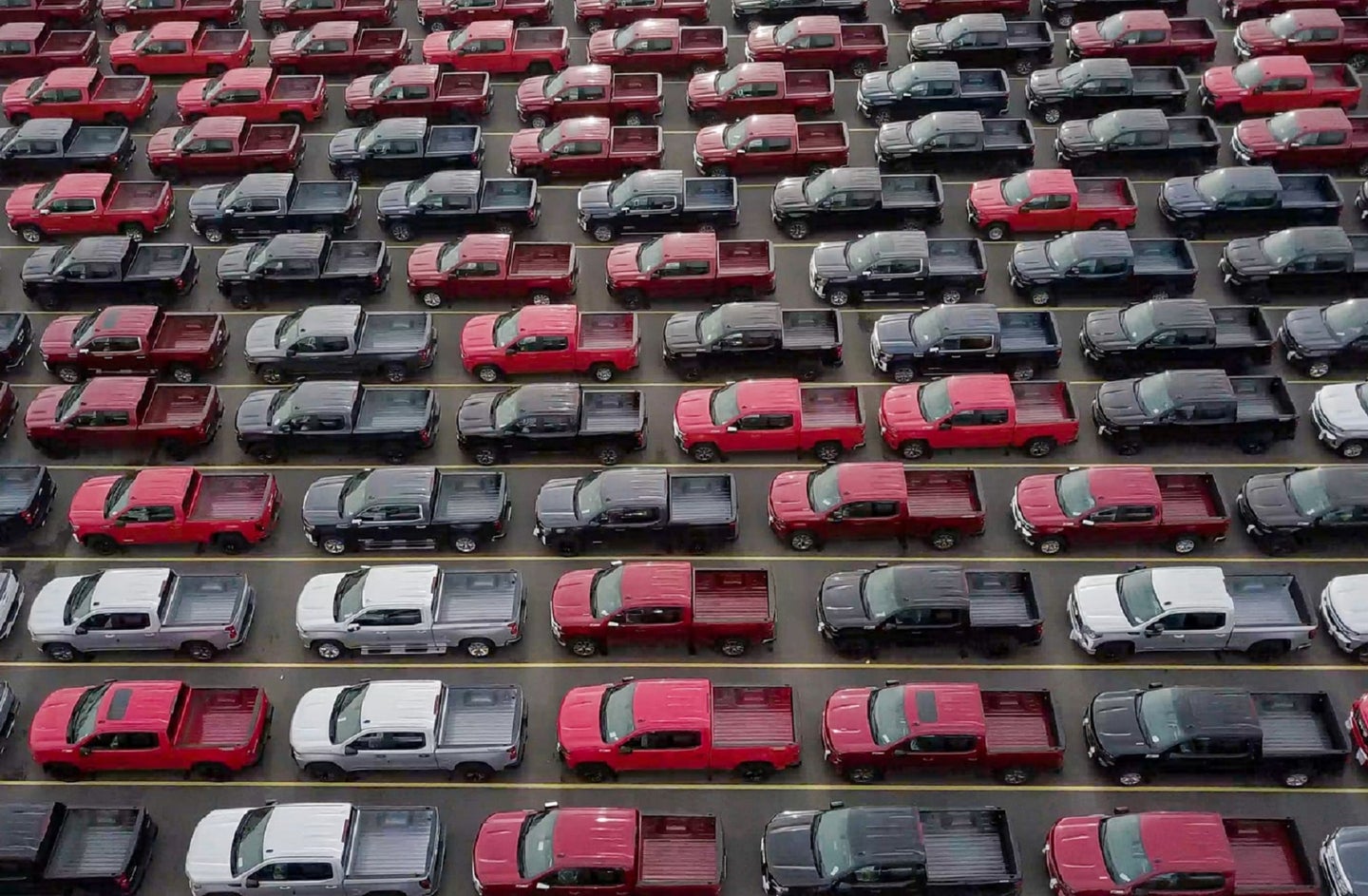 White, red, and black two-door pick-up trucks lined up in rows during the chip shortage