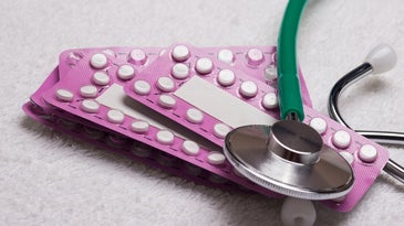 Pink birth controls pills and green stethoscope to symbolize hormone issues