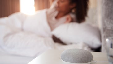 A photo of a person waking up next to a smart speaker to illustrate a story about privacy implications of the internet of things.