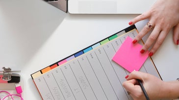 Person-writing-on-planner-with-sticky-notes