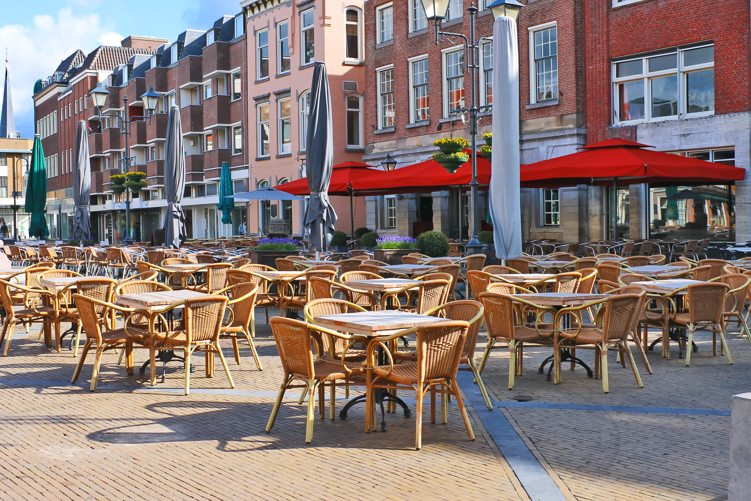 A sunny European plaza with empty tables because of the BA.2 COVID surge