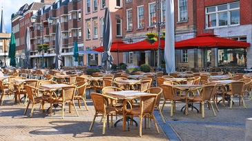 A sunny European plaza with empty tables because of the BA.2 COVID surge