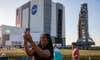 Black person with long dreads taking a selfie with a smartphone in front of the NASA SLS rocket at Kennedy Space Center in Florida