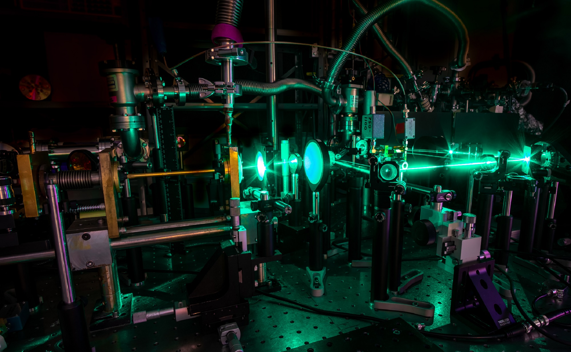 Terahertz laser setup with green lights and silver machinery in a dark room