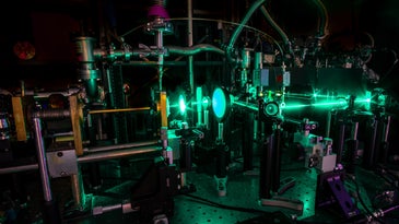 Terahertz laser setup with green lights and silver machinery in a dark room