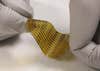 Bendable yellow chip with terahertz waves dripped by white gloved fingers