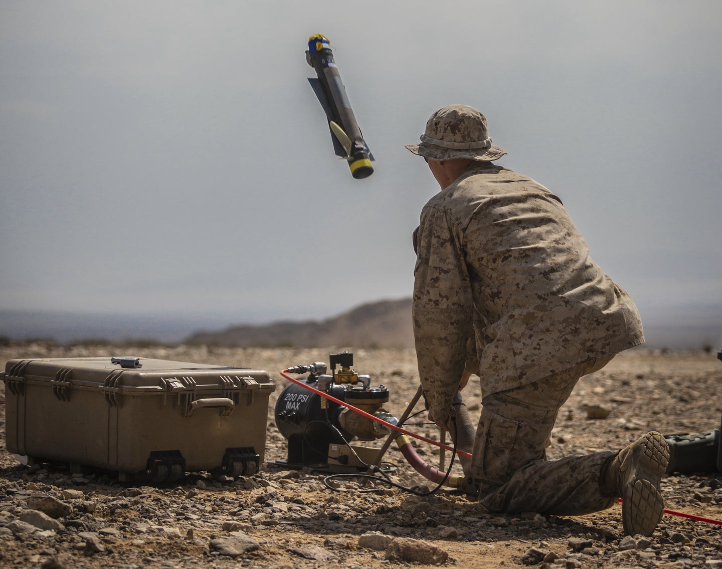 A US Marine launching a Switchblade 300 drone during training in desert terrain.