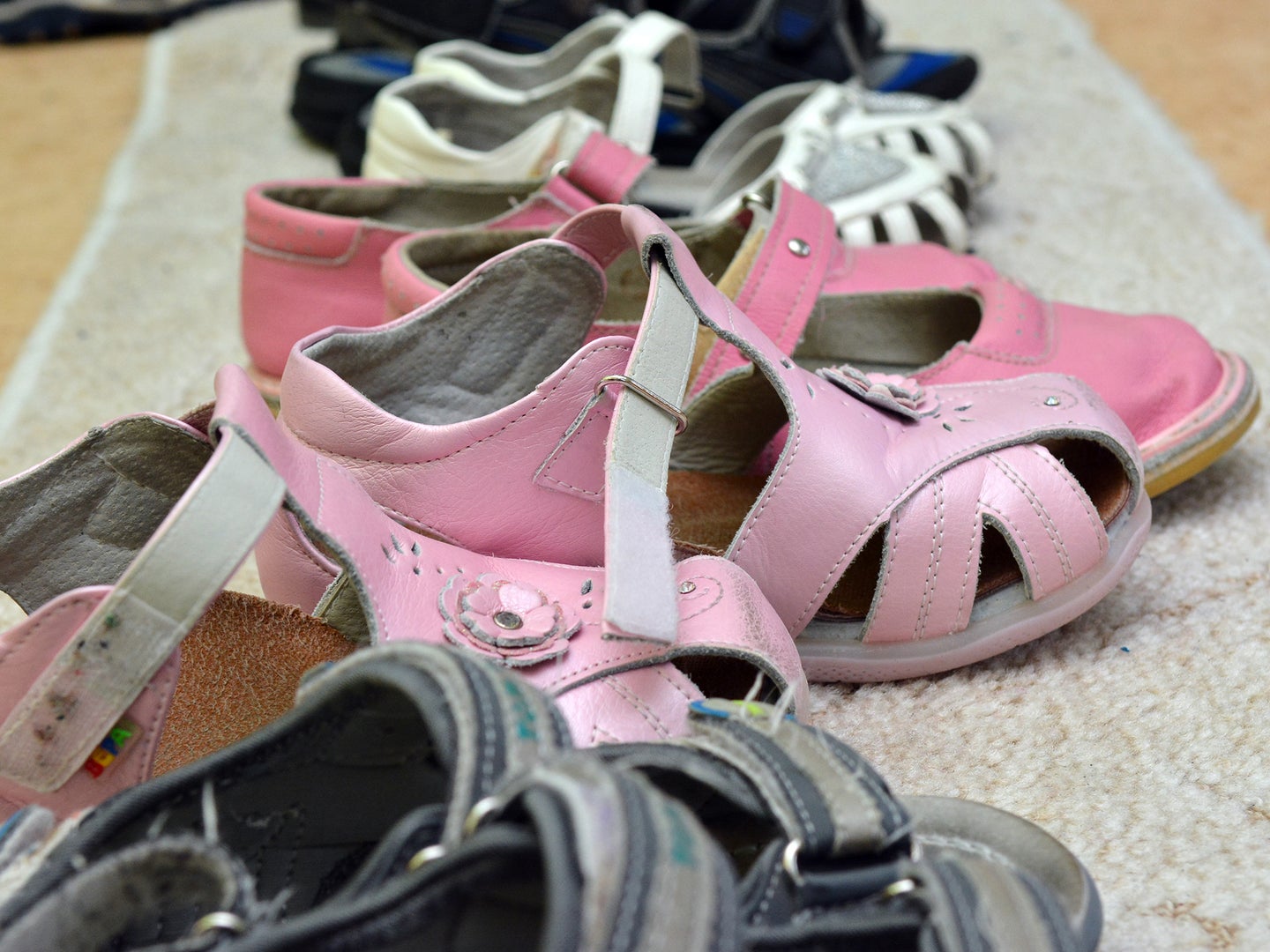 A photo of shoes on a mat at home to illustrate a story on the health risks of wearing street shoes indoors.