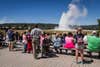 Old Faithful geyser in Yellowstone National Park with a crowd watching on a sunny summer day