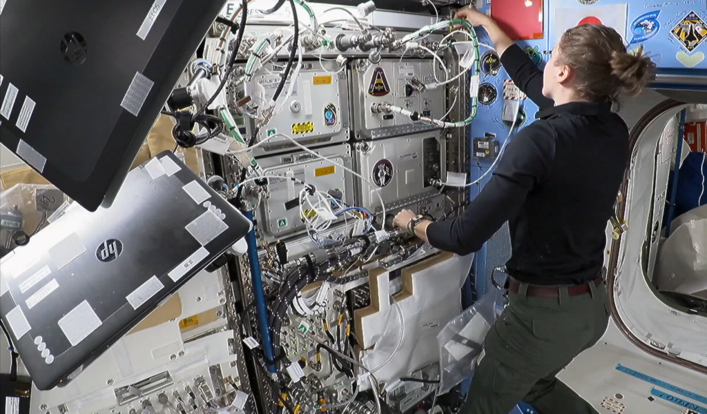 a female astronaut works on an experiment on the ISS