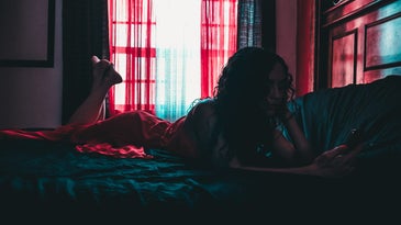 teenage girl lying on bed using phone