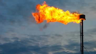Gas flare against a dark cloudy sky harnessed for energy to mine cryptocurrency