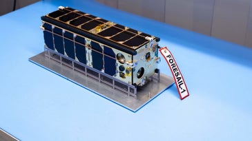 a milk carton sized satellite with solar panels around its surface