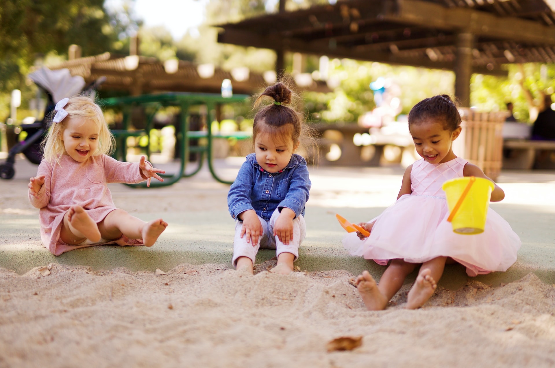 Drie kinderen in jurken die in een zandbak spelen tijdens een acute hepatitis-uitbraak in de VS en Europa