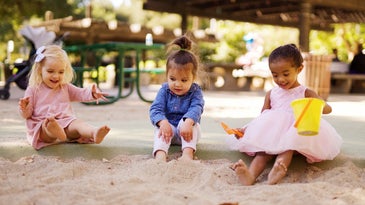 Three children in dresses playing in a sandbox during an acute hepatitis outbreak in the US and Europe