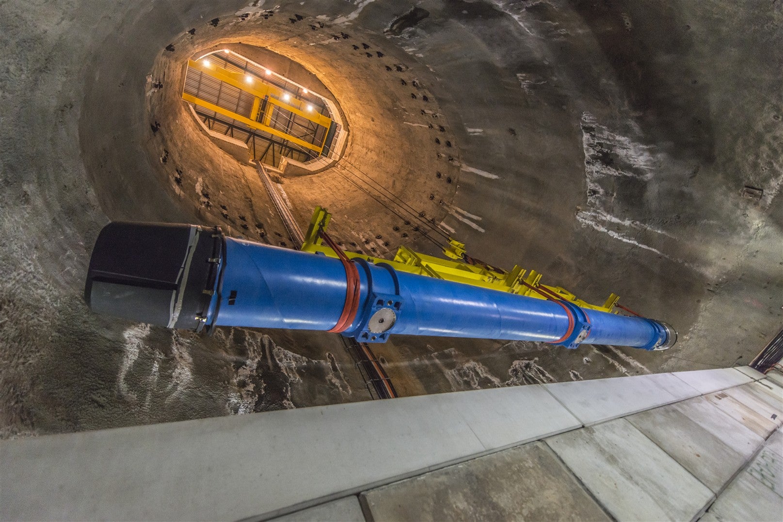Blue tube-like magnets being lifted by a crane from the Large Hadron Collider during 2013 maintenance