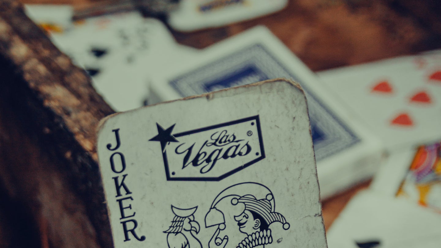Some playing cards in a wooden drawer in a workshop, with the joker in the foreground.