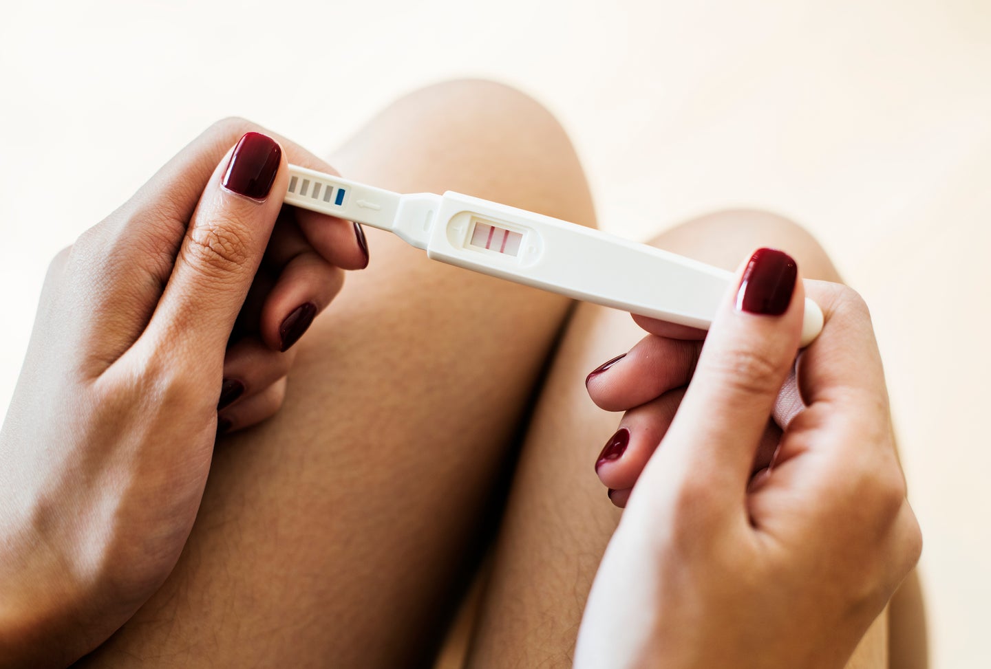 close up of a woman holding a positive pregnancy test