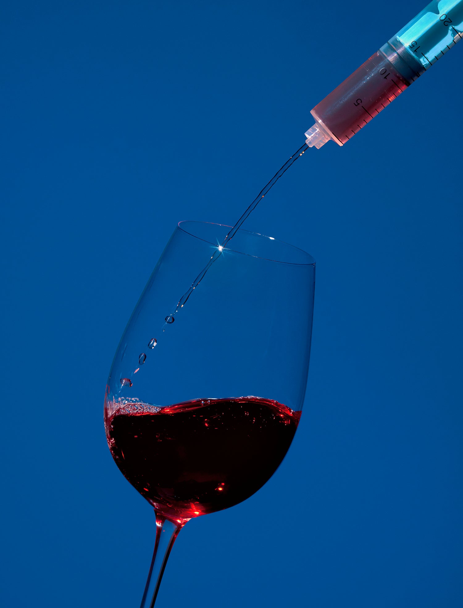 Syringe pours red wine into glass
