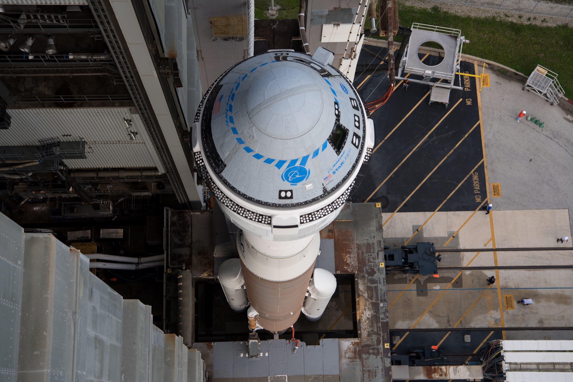 a blue and gray space capsule on top of a tall rocket positioned on a launch pad