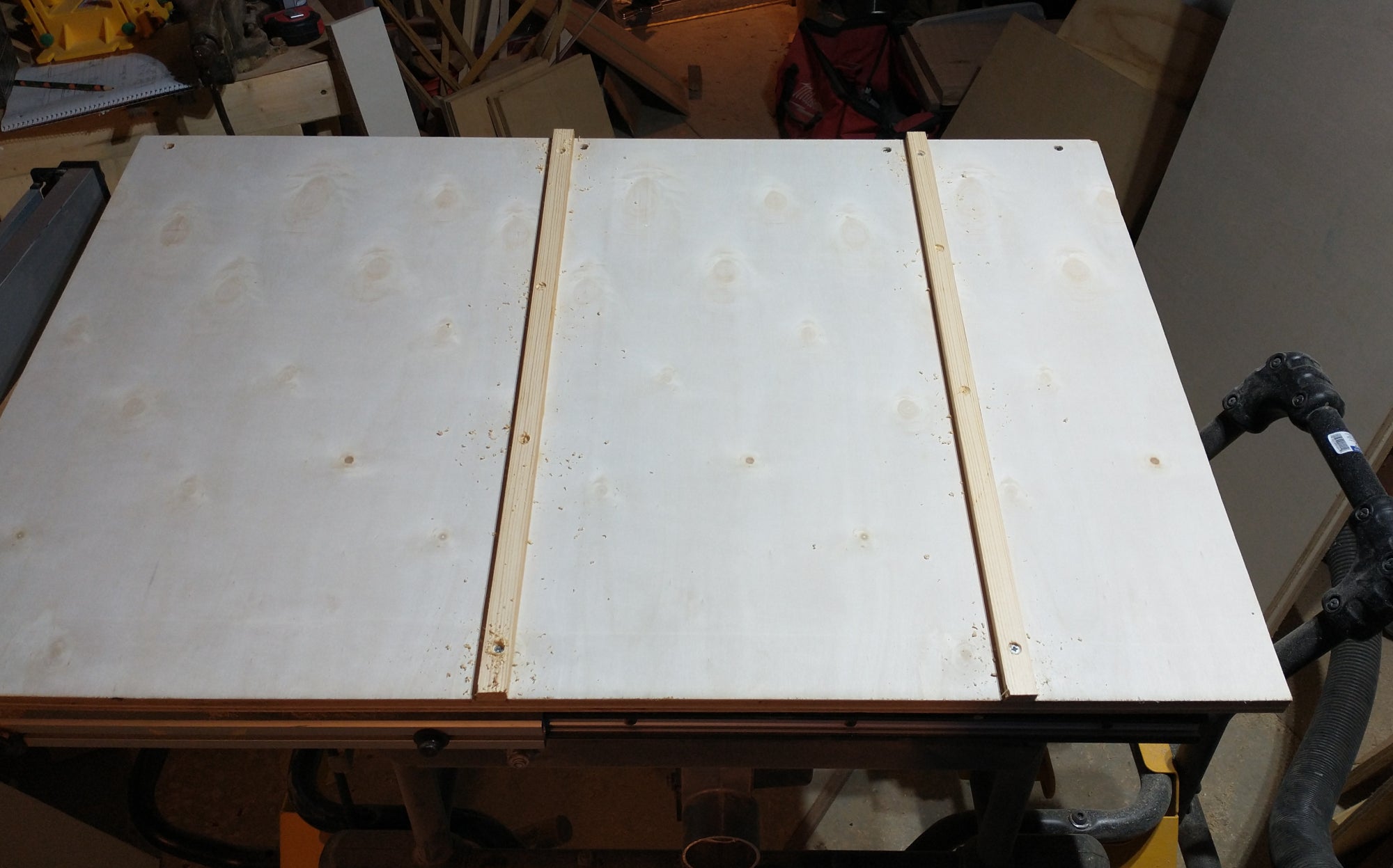 The underside of a DIY crosscut sled, showing the runners that go into the table saw's miter slots.