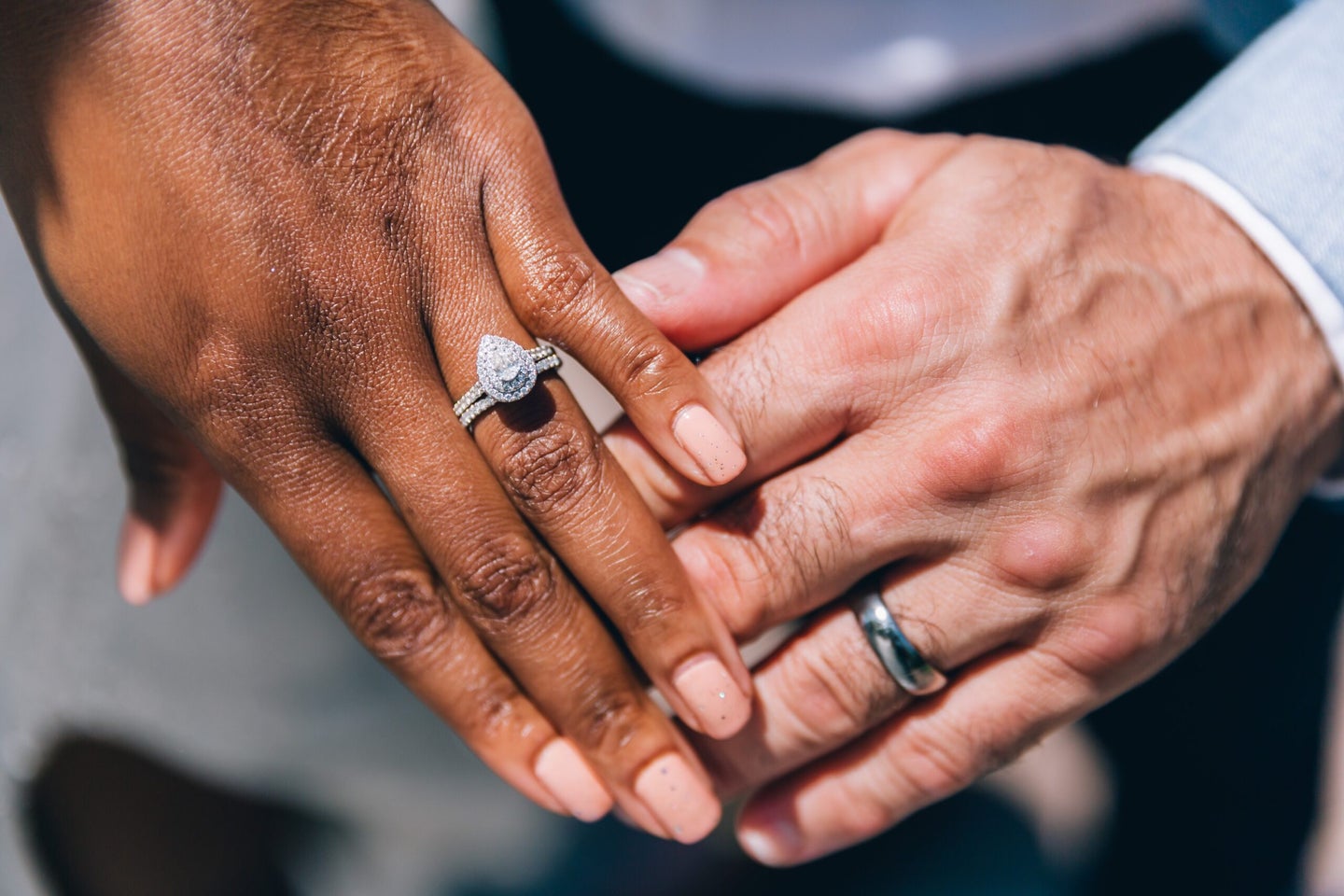 Hands of a couple wearing engagement and wedding rings.