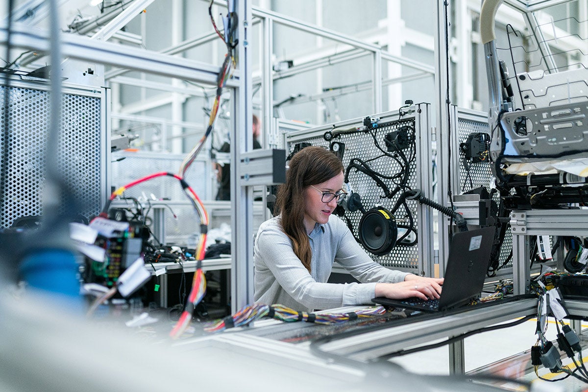 A woman works at a computer surrounded by machinery