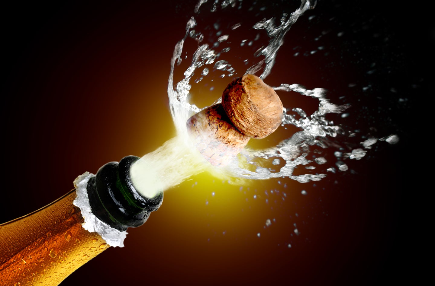 Gold and green champagne bottle with cork popped and bubbles rushing out on a black background