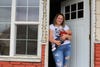 Haley Rehm holds her 2-month-old baby in the doorway of her home just across the street from the Continental mine in Butte, Montana. Rehm didn’t think about the dust often until a recent test of her 2-year-old son’s blood found elevated lead levels. (Katheryn Houghton/KHN)