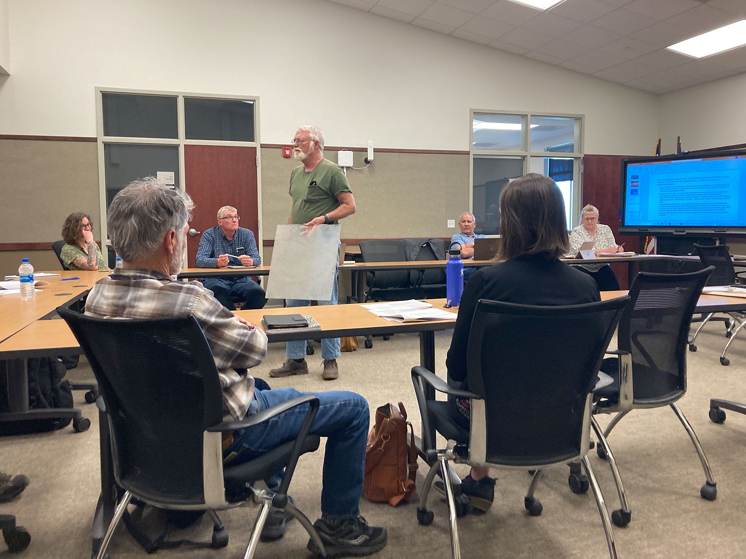 During a recent meeting to review air-quality sampling data collected in the Greeley neighborhood of Butte, Montana, resident Larry Winstel held up a square sheet of plexiglass covered in dust that he said had been on his picnic table. “This is three weeks’ worth,” Winstel said. “How much of this is being deposited over a year?” (Katheryn Houghton/KHN)