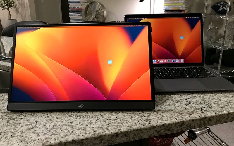 ASUS Rog Strix portable monitor showing an orange background while sitting on a kitchen counter