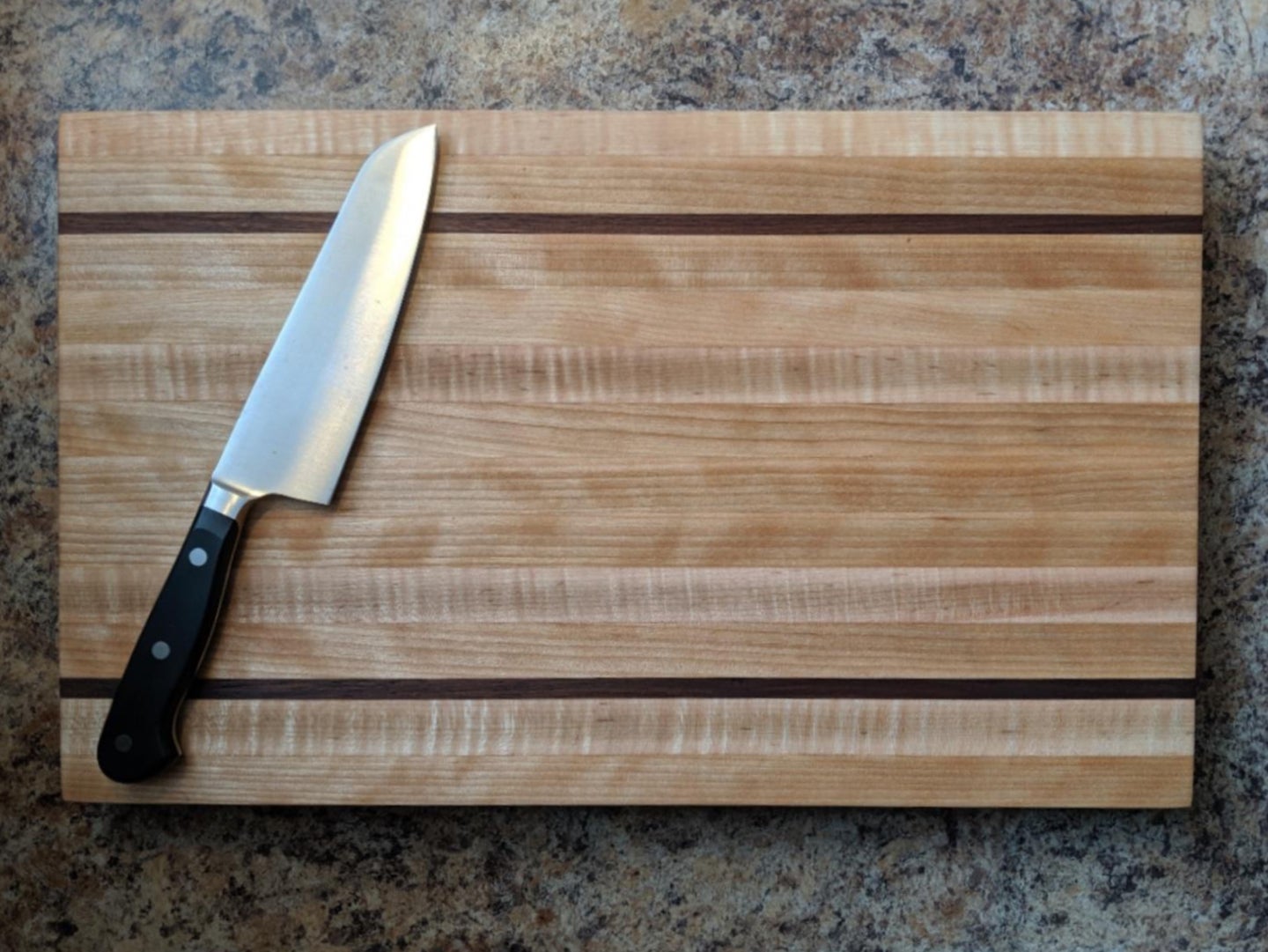 A DIY cutting board with accent borders made out of a different type of wood than the rest of the piece.