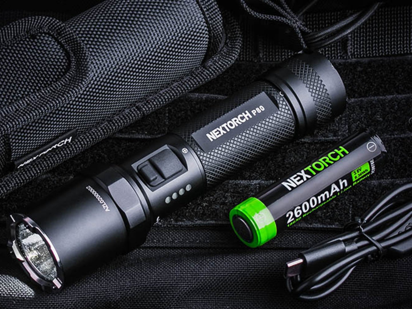 a black flashlight and a battery pack against a black fabric background