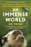 An Immense World by Ed Yong book cover with a white monkey looking up at a blue butterfly on a green background with white and gold all-caps text