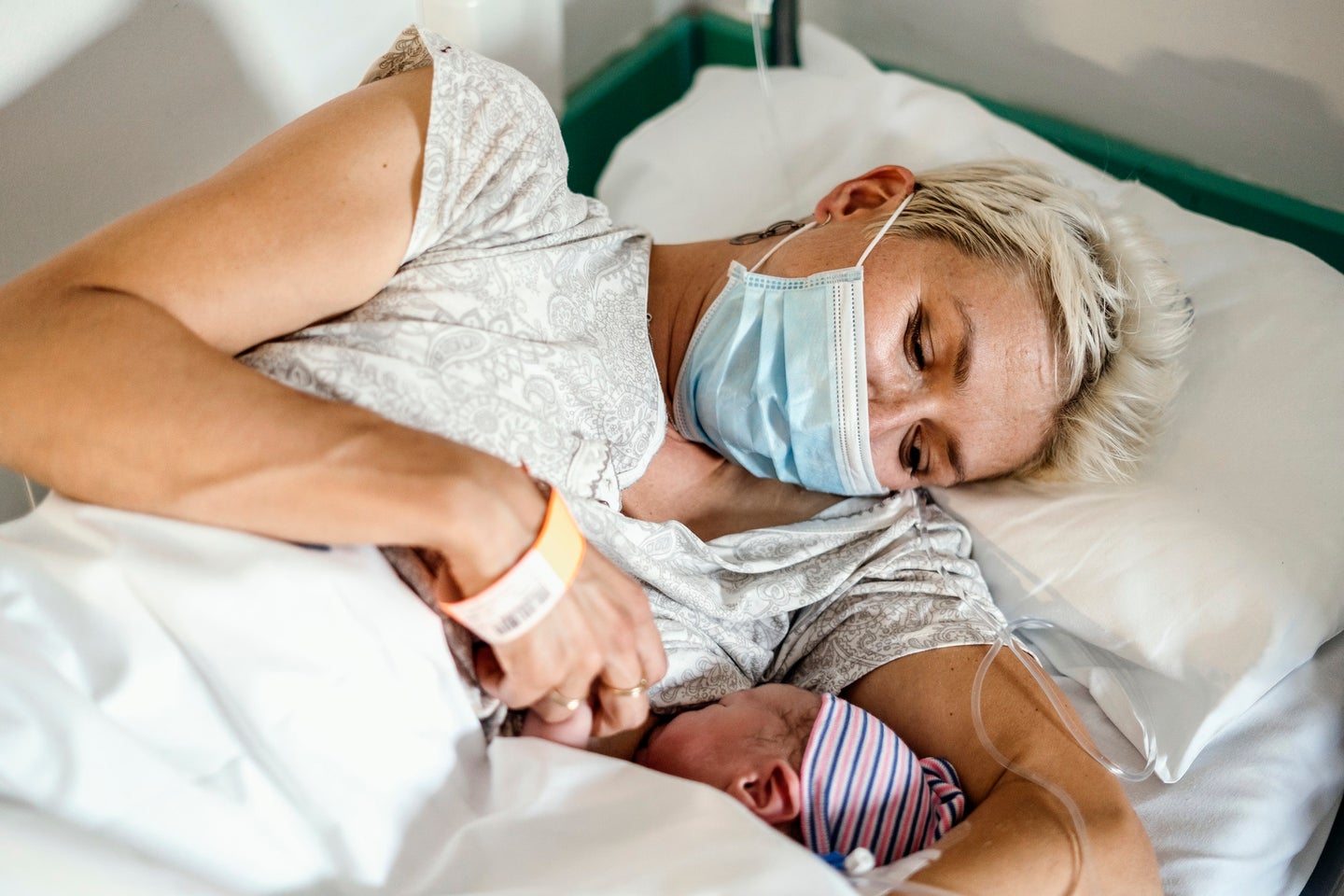 New mother nursing newborn baby while wearing a COVID mask