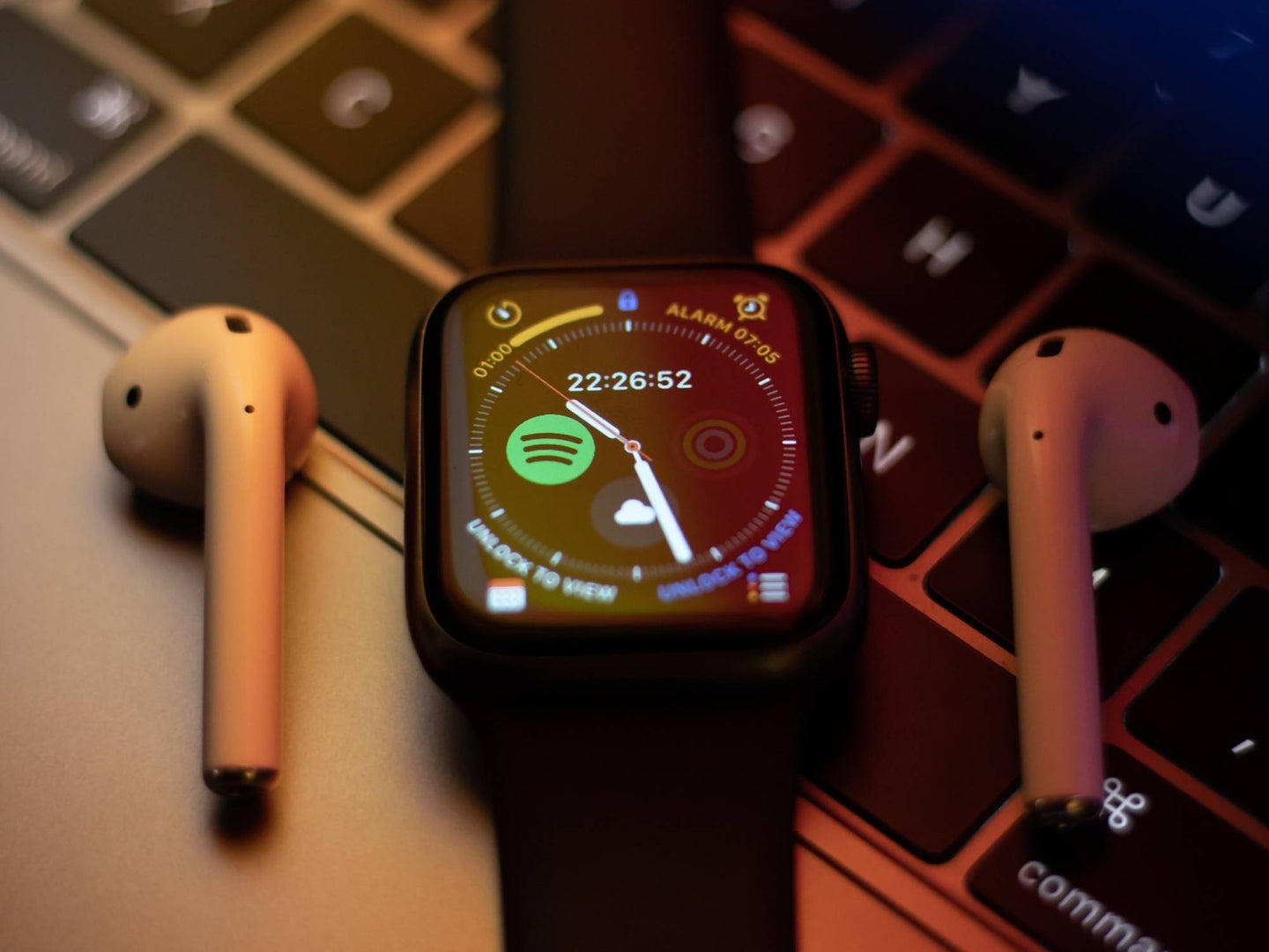 Apple watch on keyboard with airpods beside