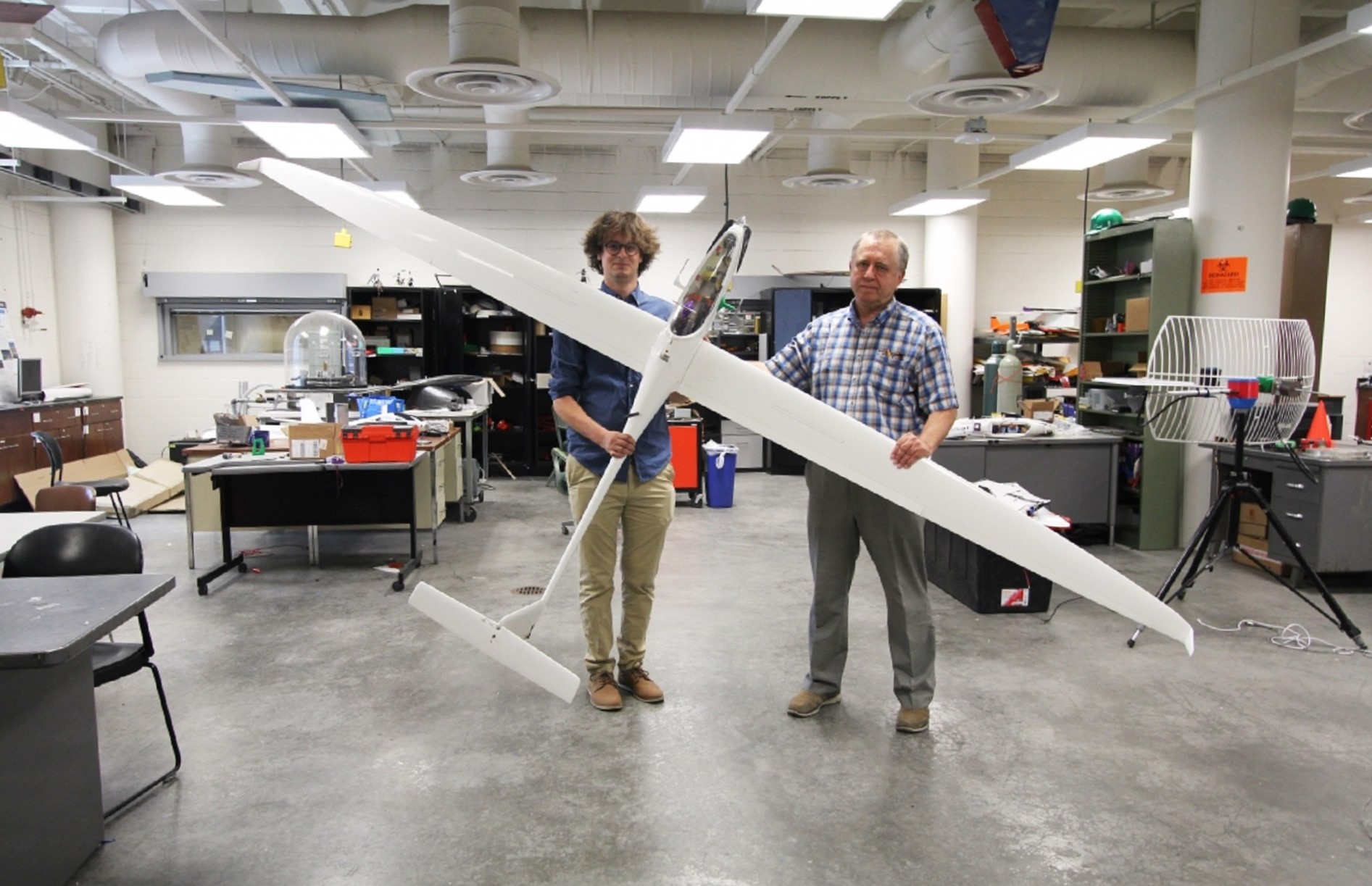 Two aerospace engineers holding a slim white Mars Sailplane in a lab at Arizona State University