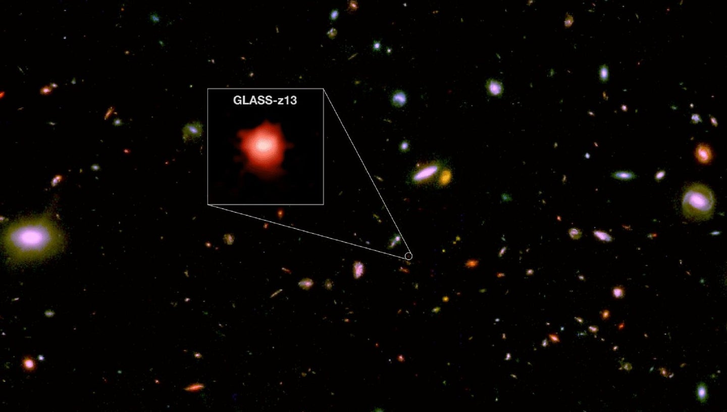 GLASS-z13 galaxy glowing red in hazy yellow stars from the James Webb Space Telescope NIRCam