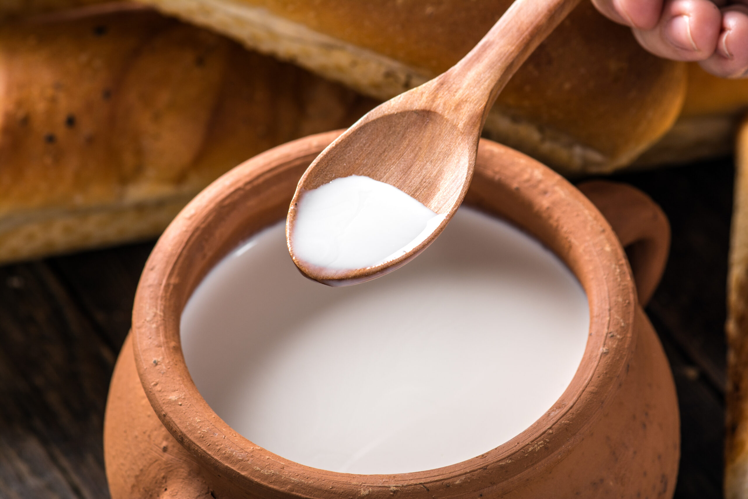 A clay pot filled with milk, with a spoon of milk over it.