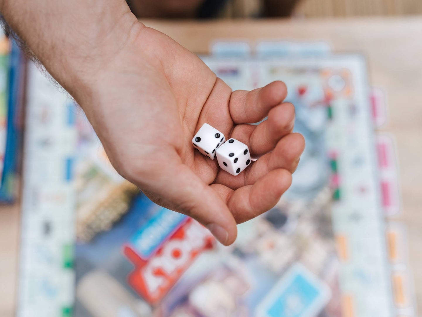 hand holding dice with board game on background
